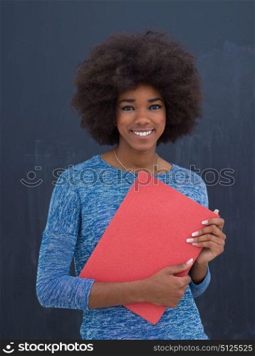portrait of a beautiful friendly African American woman with a curly afro hairstyle and red folder isolated on a gray background