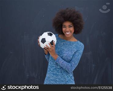 portrait of a beautiful friendly African American woman with a curly afro hairstyle and lovely smile holding a soccer ball isolated on a gray background