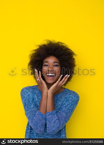 portrait of a beautiful friendly African American woman with a curly afro hairstyle and lovely smile isolated on a Yellow background