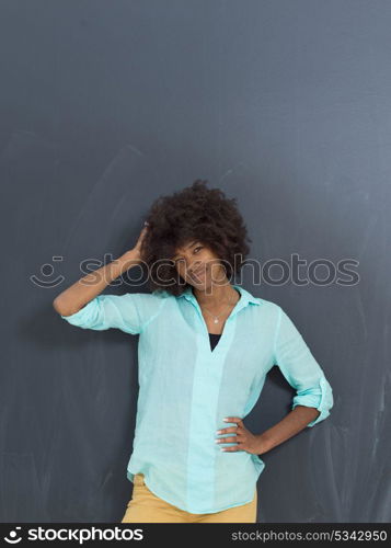 portrait of a beautiful friendly African American woman with a curly afro hairstyle and lovely smile in front of gray chalkboard