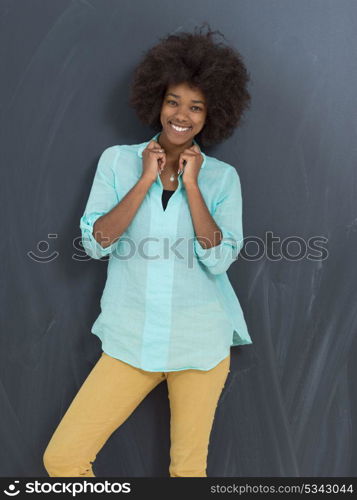 portrait of a beautiful friendly African American woman with a curly afro hairstyle and lovely smile in front of gray chalkboard