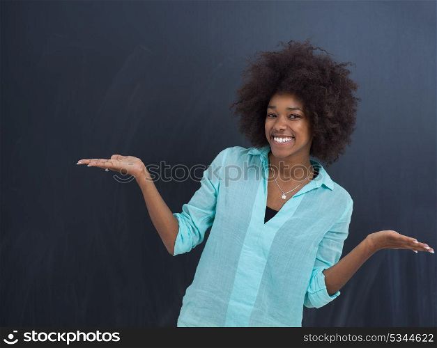 portrait of a beautiful friendly African American woman with a curly afro hairstyle and lovely smile in front of gray chalkboard
