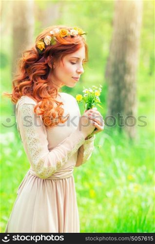 Portrait of a beautiful gentle woman in a forest, female enjoying aroma of a little bouquet of wild flowers, beauty of spring nature