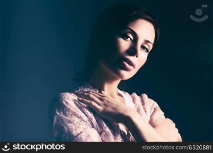 Portrait of a beautiful gentle woman wearing lace dress over dark background, tender elegant bride in the morning, feminine and romantic look