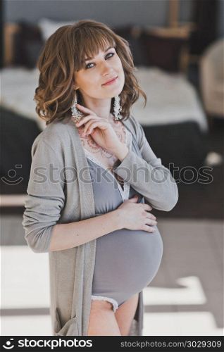 Portrait of a beautiful girl expecting a baby.. Happy pregnant girl on the background of a bright room 1043.. Happy pregnant girl on the background of a bright room 1043.