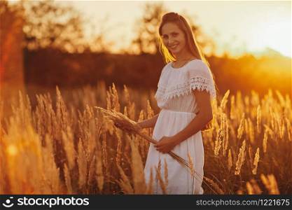Portrait of a beautiful girl in a white dress in the field at sunset. Portrait of a beautiful girl in a white dress in the field at sunset. Summer. unity with nature.