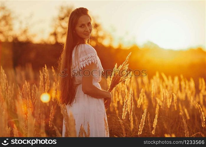Portrait of a beautiful girl in a white dress in the field at sunset. Portrait of a beautiful girl in a white dress in the field at sunset. Summer. unity with nature.