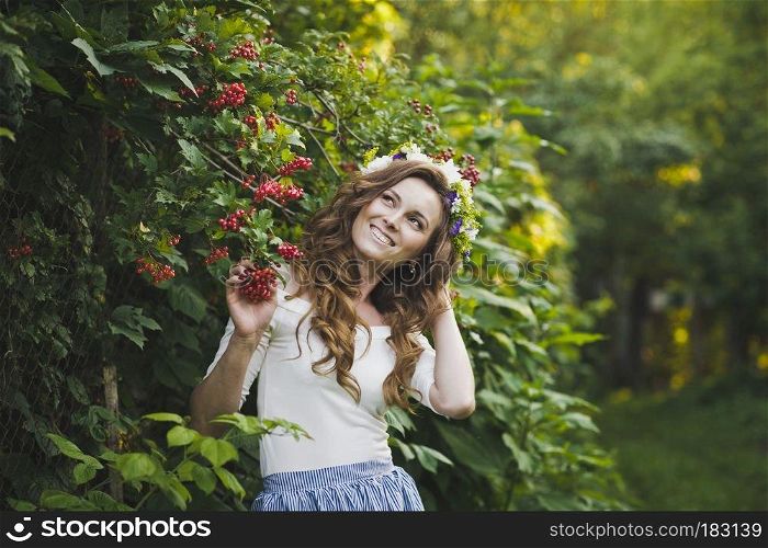 Portrait of a beautiful girl near the Bush of the mountain ash.. Portrait of a girl with a wreath on his head in the garden 4797.