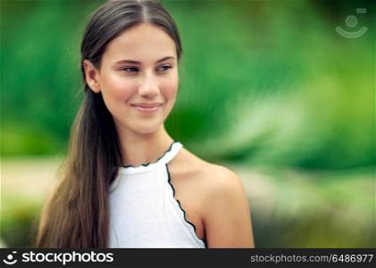 Portrait of a beautiful girl on blurry green natural background, nice attractive female without makeup, genuine beauty of young woman. Beautiful girl outdoors