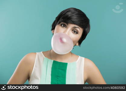 Portrait of a beautiful girl with a bubble gum on the mouth, against a blue background