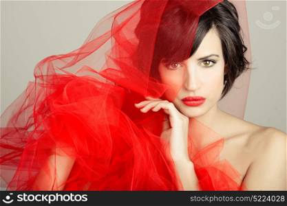 Portrait of a beautiful girl with a red tulle. Studio photograph