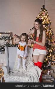 Portrait of a beautiful girl with her daughter on the background of sparkling Christmas garlands.. Mother and daughter on the background of sparkling Christmas garlands 9