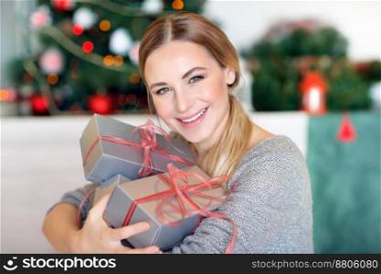 Portrait of a beautiful happy woman with gift boxes in hands sitting in a beautiful decorated room at home, happy Christmas holidays. Happy woman with Christmas gifts