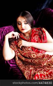 Portrait of a beautiful Indian woman sleeping on a velvet sofa