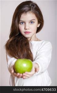 Portrait of a beautiful little girl holding a green apple, isolated on white background