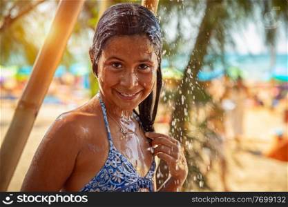 Portrait of a beautiful little girl on the beach resort, happy child taking shower on the beach, having fun outdoors, enjoying summer holidays near the sea