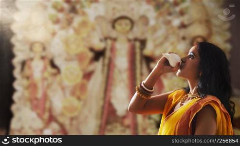 Portrait of a beautiful Married Bengali woman blowing , during Durga puja celebrations
conch shell at Durga puja 