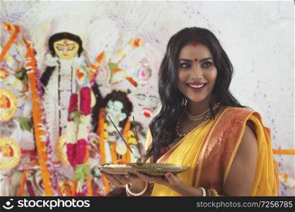 Portrait of a beautiful Married Bengali woman holding Puja Thali, during Durga puja celebrations