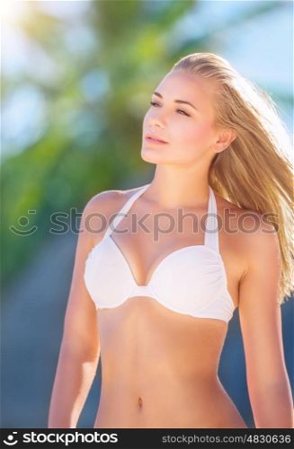 Portrait of a beautiful model on the beach posing in white bikini, enjoying luxury resort on an island, getaway travel destination on summer vacation time and holidays&#xA;