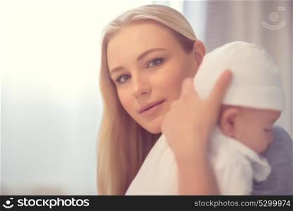 Portrait of a beautiful mother with cute little baby at home, attractive woman enjoying parenthood, happy young family, new life concept