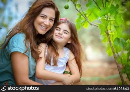 Portrait of a beautiful mother with her cute little daughter with pleasure spending time together in fresh green garden, happy family life. Happy mother and daughter portrait