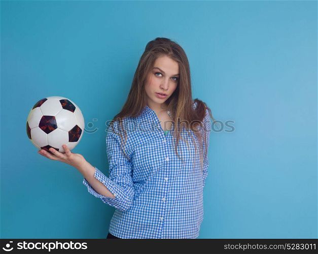 Portrait of a beautiful positive young woman while playing with a soccer ball isolated on blue background