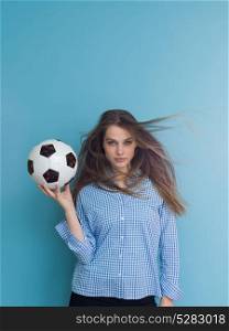 Portrait of a beautiful positive young woman while playing with a soccer ball isolated on blue background