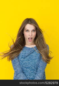 Portrait of a beautiful positive young woman while playing with her long silky hair isolated on yellow background