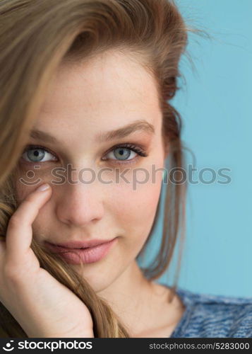 Portrait of a beautiful positive young woman while playing with her long silky hair isolated on blue background