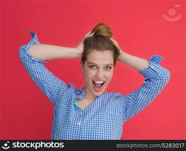 Portrait of a beautiful positive young woman while playing with her long silky hair isolated on red background