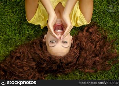 Portrait of a beautiful readhead woman lying on the grass