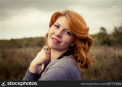 Portrait of a beautiful redhair girl in the autumn park. Caucasian race.