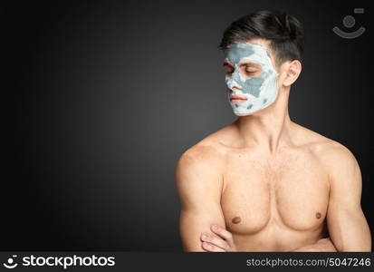 Portrait of a beautiful relaxed young man with a facial mud clay mask, face and body skin care treatment.