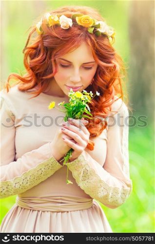 Portrait of a beautiful romantic girl enjoying aroma of a gentle wild flowers in the spring park, sensual fashion look of the forests nymph