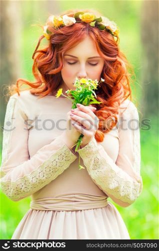 Portrait of a beautiful romantic girl with closed eyes enjoying aroma of a gentle wild flowers in the spring park, sensual fashion look of the forests nymph