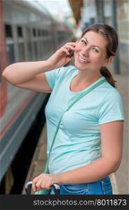 portrait of a beautiful smiling girl with a phone at the station
