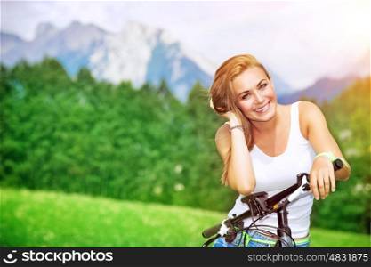 Portrait of a beautiful smiling woman enjoying bright sunny day in the Alps, mountainous tour on bicycle, happy active summer vacation