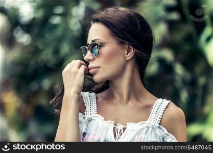 Portrait of a beautiful stylish woman over nature background, relaxation on the tropical islands, enjoying summer vacation on the exotic resort. Portrait of a beautiful woman