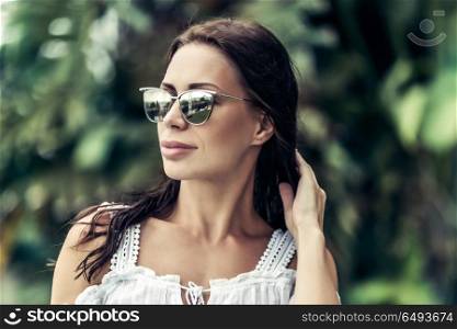 Portrait of a beautiful stylish woman over nature background, relaxation on the tropical island, enjoying summer vacation on the exotic resort. Beautiful woman on summer vacation