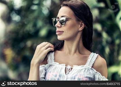 Portrait of a beautiful stylish woman over nature background, relaxation on the tropical island, enjoying summer vacation on exotic resort. Portrait of a beautiful woman