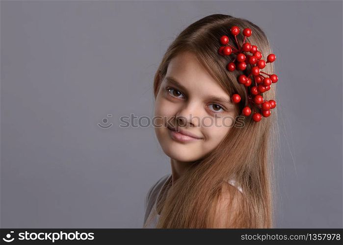 Portrait of a beautiful teenage girl with a bunch of berries in her hand and in her hair