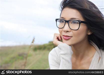Portrait of a beautiful thoughtful chinese asian girl or young woman outside wearing glasses