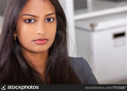 Portrait of a beautiful thoughtful young successful female Asian Indian business woman or businesswoman in office