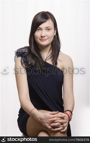 Portrait of a beautiful twenty-year-old girl, brunette. Girl sits on the chair and smiling looks in the frame