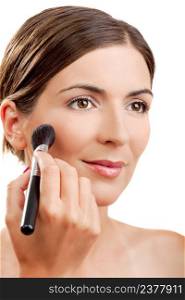 Portrait of a beautiful woman applying make-up with a brush