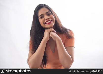 portrait of a beautiful woman looking at camera and smiling with resting chin on  hands