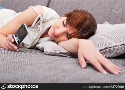 Portrait of a beautiful woman lying on sofa, sending a sms