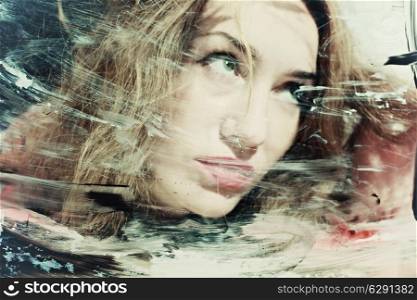 Portrait of a beautiful woman through the dirty glass closeup