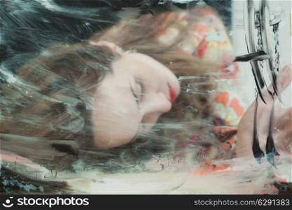 Portrait of a beautiful woman through the dirty glass closeup