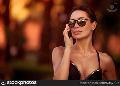 Portrait of a beautiful woman wearing stylish sunglasses and bikini, gorgeous female model outdoors, summer vacation in style